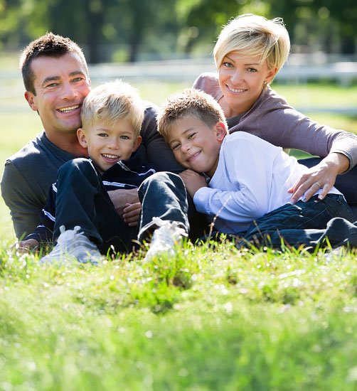 Happy family smiling confidently with straight teeth after completing Invisalign treatment.
