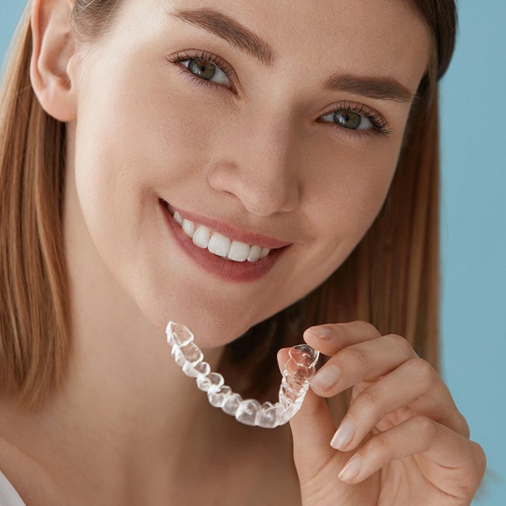 Woman holding clear aligners at a dental clinic in Stafford, VA